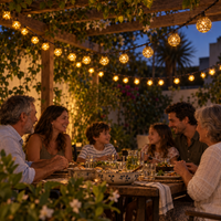 Familia reunida alrededor de una mesa en el jardín bajo una guirnalda de bolas marroquíes doradas encendidas.